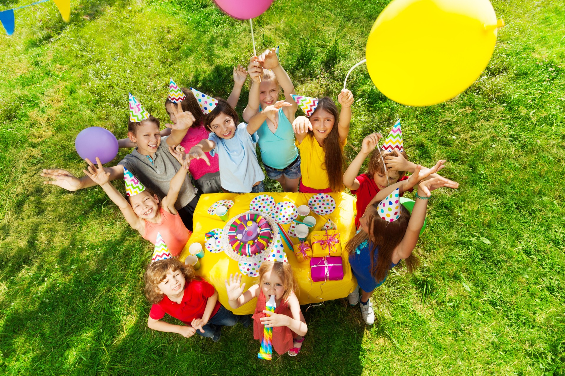 Gruppo di bambini che ridono in piedi intorno alla torta B-day